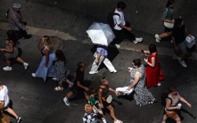 Photo: pedestrians, including a person holding an umbrella to block UV rays, walk on Times Square in New York
